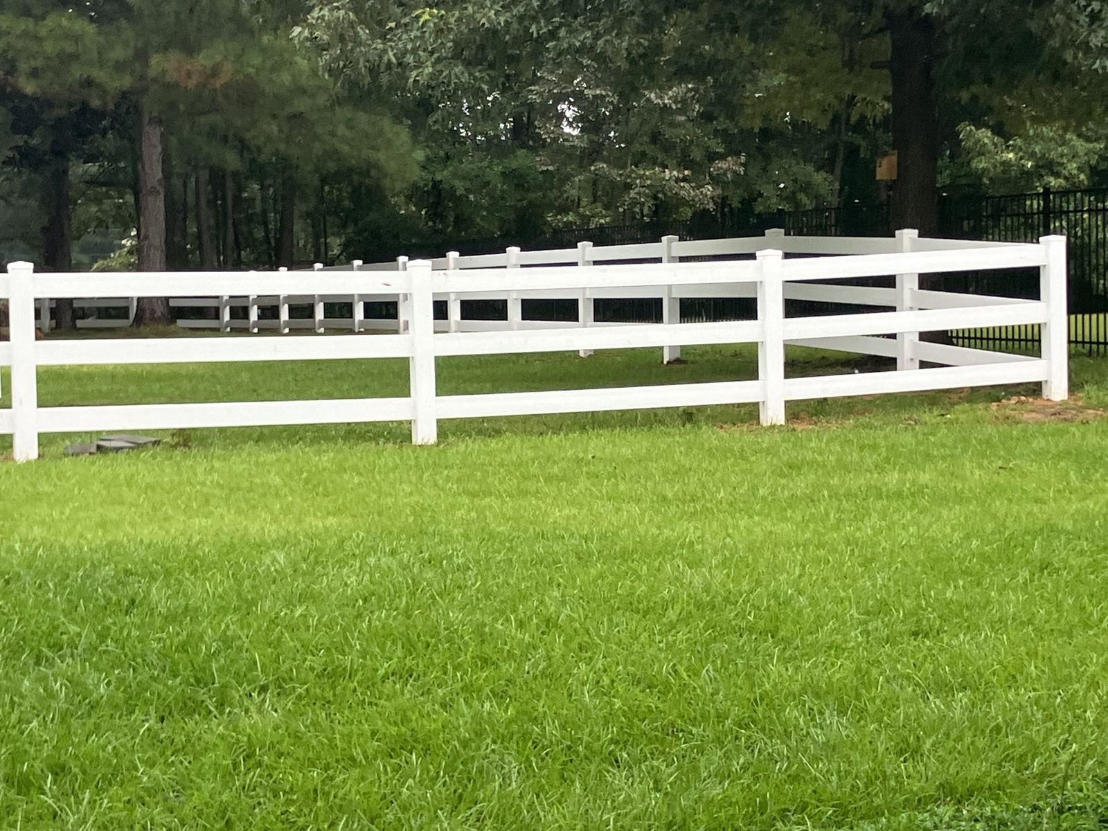 White ranch-style rail fence on a green lawn