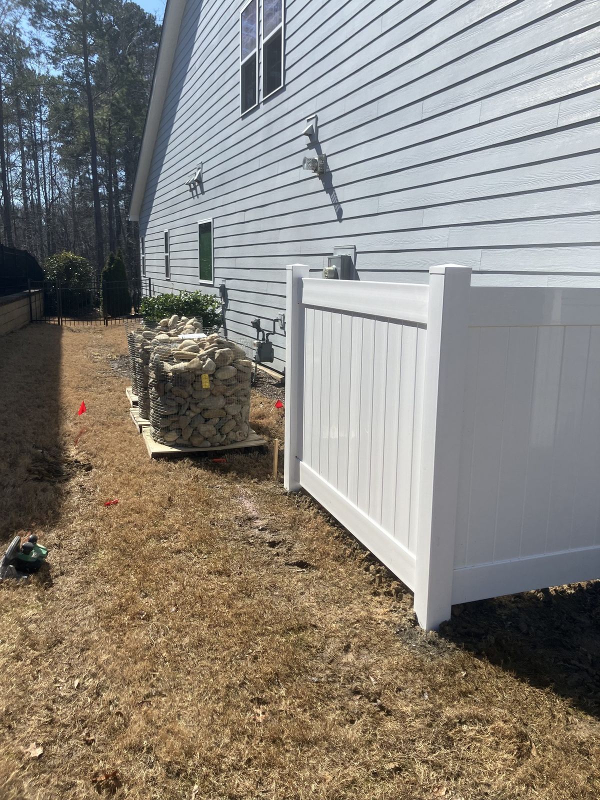 White vinyl garbage can corral along the side of a house