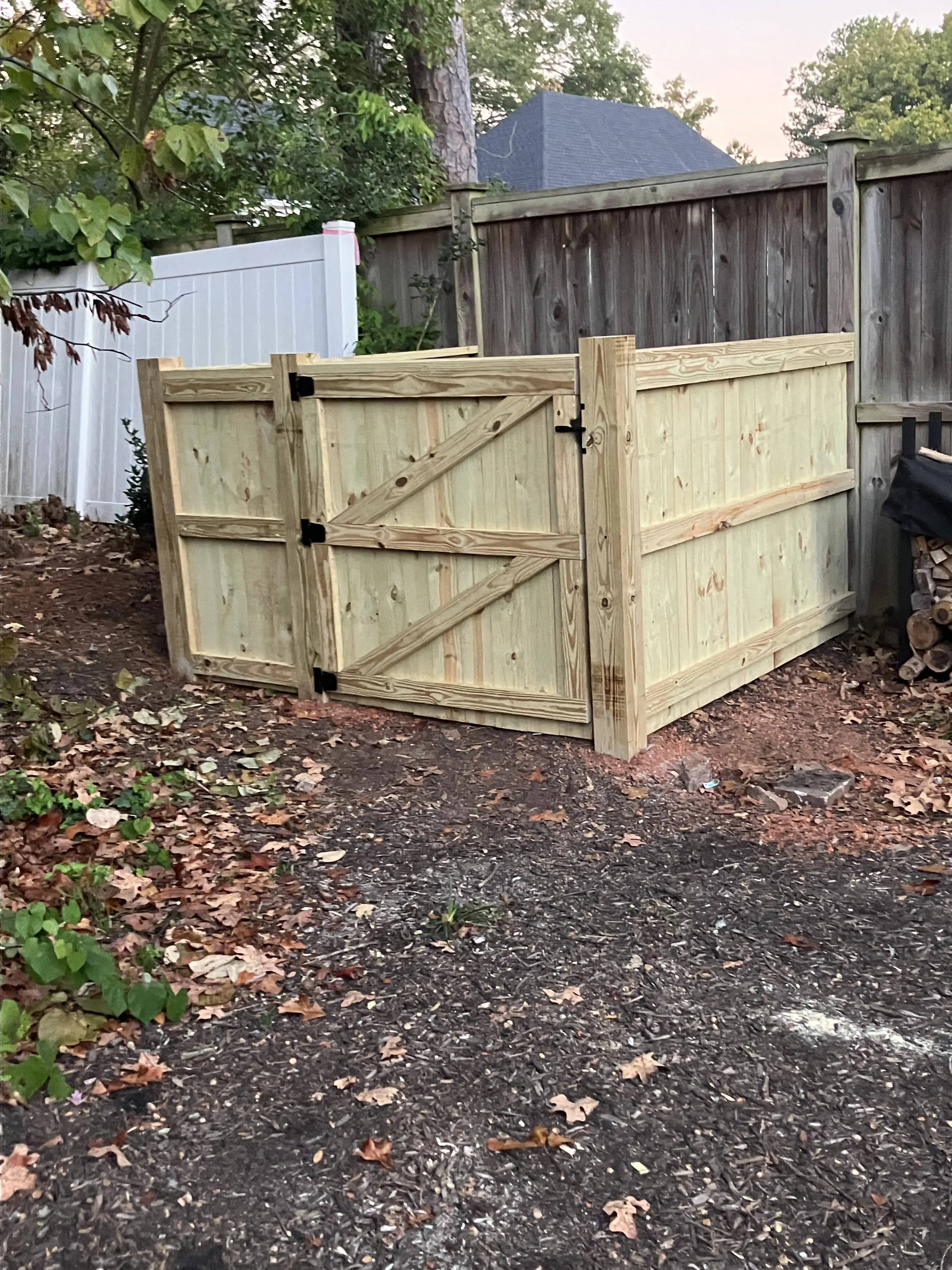Finished wood garbage can corral matched to the yard's fence line