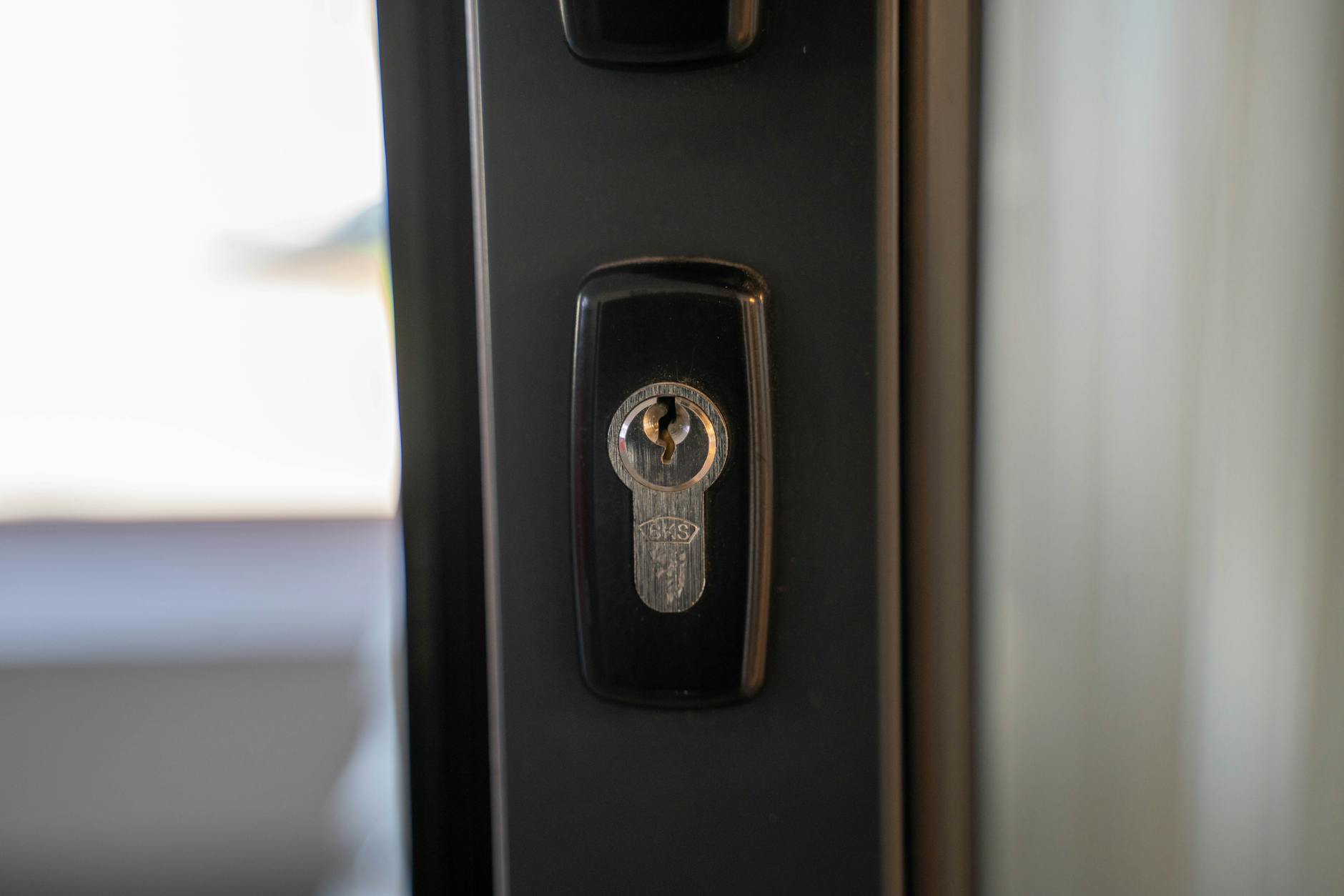 Close-up of a keyed lock on a dark front door